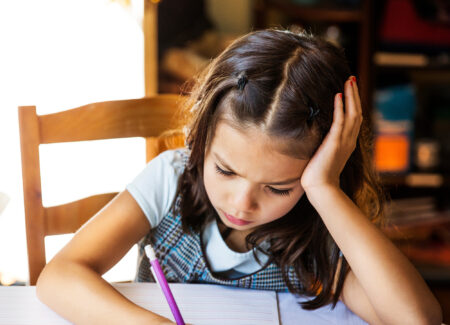 Young girl doing homework at kitchen table.