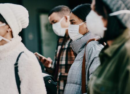 Traveling people wearing face mask in a covid pandemic in crowd, public or airport border with passport or travel restrictions. Foreigners wearing protection to prevent the spread of diseases abroad.