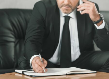 Business man taking notes while on a phone call.
