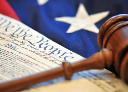 Constitution laying on top of American flag with a gavel on top.