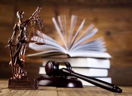 Statue of Lady Justice next to an open book and a gavel.
