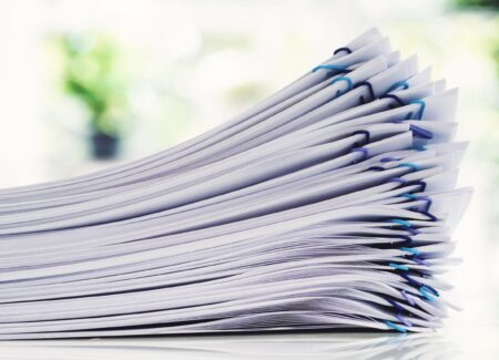 Stack of documents with blue paperclips and a green background.