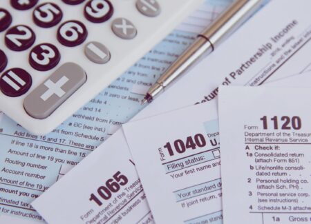 Tax season. calculator, pen on US tax form background.